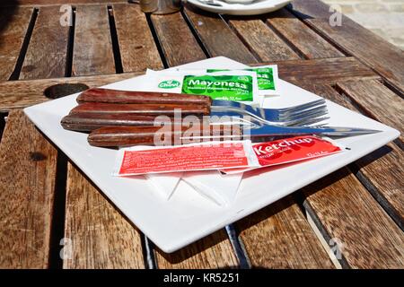 Posate con bustine di ketchup e maionese su una tavola di legno all'interno della cittadella, Victoria (Rabat), Gozo, Malta, l'Europa. Foto Stock
