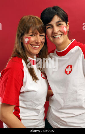 Foto di due femmine Swiss gli appassionati di sport sorridente e fare il tifo per i loro team. Foto Stock