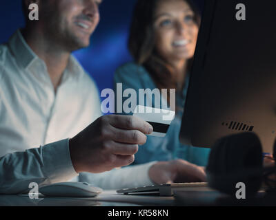 Sorridenti giovane facendo shopping online insieme, l'uomo è in possesso di una carta di credito Foto Stock