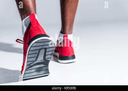 Messa a fuoco selettiva di African American sportsman in sneakers su grigio Foto Stock