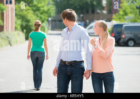 La donna grida al suo fidanzato guardando un'altra donna Foto Stock