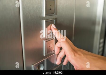 La femmina mano, premendo il primo pulsante a pavimento in ascensore Foto Stock