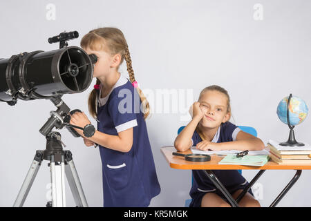 Una bambina guarda attraverso un telescopio, l'altra ragazza è in attesa dei risultati triste Foto Stock