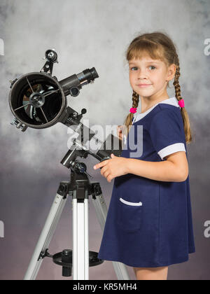 Ragazza amante di astronomia sorge accanto al telescopio e guardato dentro il telaio Foto Stock