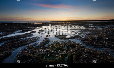 Sunderland, Regno Unito, 18 dicembre 2017. Chiari cieli portato durante la notte il gelo e una chiara sunrise a Sunderland. Roker beach è coperto di alghe come risultato delle recenti tempeste. (C) Paolo Swinney/Alamy Live News Foto Stock