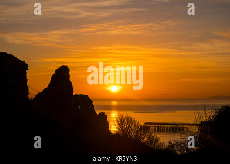 Hastings, East Sussex, UK 18th Dec 2917. Tramonto invernale colorato mentre il sole affonda dietro il Castello di Hastings e il molo. Foto Stock