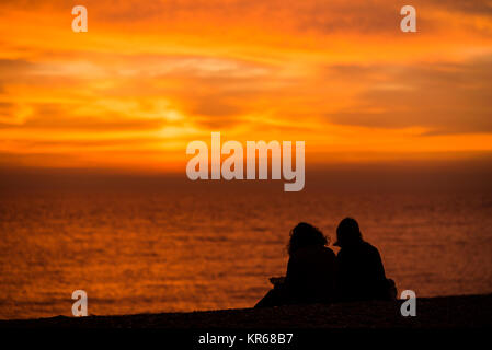 Brighton, East Sussex. 19 dicembre 2017. Regno Unito meteo. Rosso brillante del cielo al tramonto alla fine della giornata in cui un gregge di migliaia di storni mettere su un display murmuration sopra Brighton il Molo Ovest. Credito: Francesca Moore/Alamy Live News Foto Stock