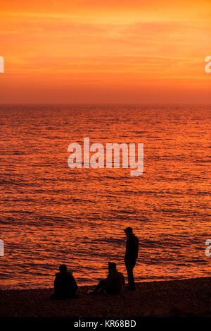 Brighton, East Sussex. 19 dicembre 2017. Regno Unito meteo. Rosso brillante del cielo al tramonto alla fine della giornata in cui un gregge di migliaia di storni mettere su un display murmuration sopra Brighton il Molo Ovest. Credito: Francesca Moore/Alamy Live News Foto Stock