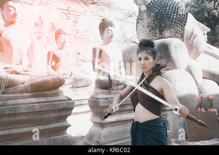 Bella donna asiatica che pongono in Thai antichi guerrieri di Wat Phutthaisawan tempio in al parco storico di Ayutthaya ,Thailandia. Foto Stock