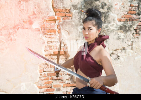Bella donna asiatica che pongono in Thai antichi guerrieri di Wat Phutthaisawan tempio in al parco storico di Ayutthaya ,Thailandia. Foto Stock