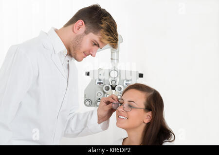 Ottico maschio indossando occhiali da vista per la donna Foto Stock