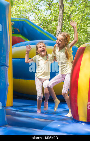 Due ragazze smorfie felicemente saltando su un trampolino gonfiabile Foto Stock