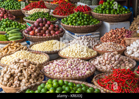 Angolo alto close up di cestelli spezie e verdure in un mercato, compresi peperoncini rossi, tigli, aglio, zenzero. Foto Stock