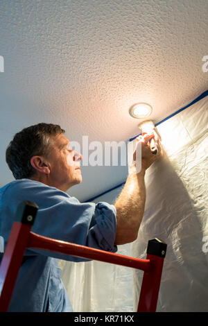 Senior adulto uomo pittura soffitto della cucina Foto Stock