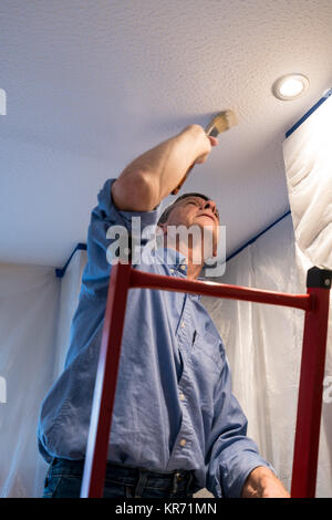 Senior adulto uomo pittura soffitto della cucina Foto Stock