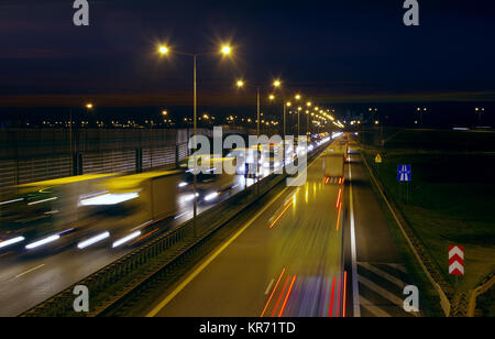 Un sacco di camion e di automobili su una strada affollata in ora di punta. Una lunga esposizione foto del traffico autostradale di notte. Foto Stock
