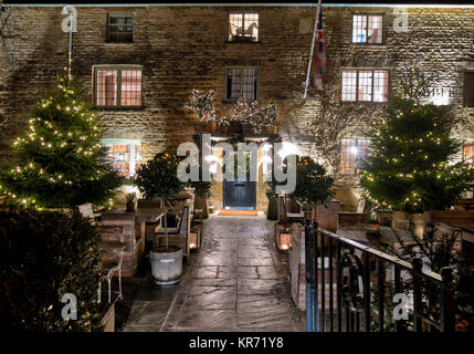 Il Coniglio selvatico pub con alberi di natale e decorazioni di notte in Kingham in dicembre. Kingham, Cotswolds, Oxfordshire, Inghilterra Foto Stock