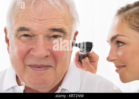 Medico donna esaminando orecchio del paziente Foto Stock