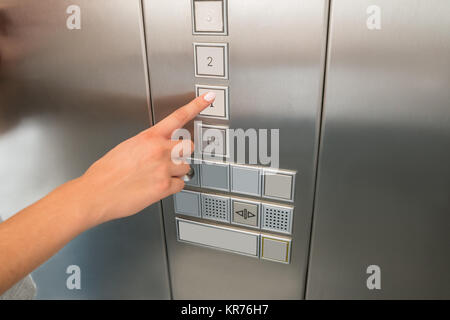 La femmina mano, premendo il primo pulsante a pavimento in ascensore Foto Stock