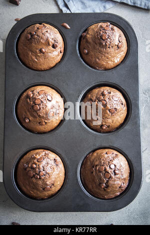 Doppio muffin al cioccolato con gocce di cioccolato in bakeware. Cioccolato artigianale pasticceria per la colazione o per dessert. Foto Stock