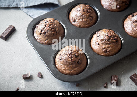 Doppio muffin al cioccolato con gocce di cioccolato in bakeware. Cioccolato artigianale pasticceria per la colazione o per dessert. Foto Stock