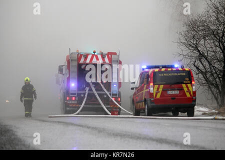 SALO, Finlandia - 16 febbraio 2014: pompiere emerge dal fumo pesante al fuoco scena di Salo impianto per cemento. Foto Stock