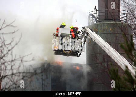 SALO, Finlandia - 16 febbraio 2014: Vigili del Fuoco estinguere il fuoco su una gru idraulica piattaforma Salo impianto per cemento. Foto Stock