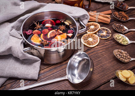 Vin brulé in una pentola con maniglie e gli ingredienti per la realizzazione di un fatto in casa bevanda alcolica su un di legno marrone, sfondo close up Foto Stock