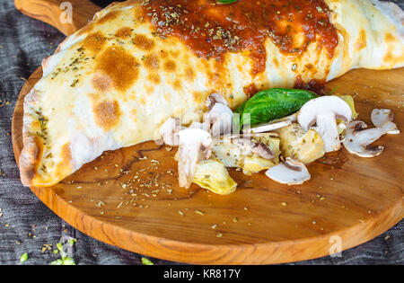 Calzone pizza, riempito di erbe, formaggio e pomodori Foto Stock