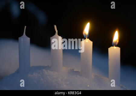 Due white candele accese all'aperto nella neve Foto Stock