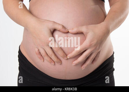 Donna incinta tenendo le sue mani sulla pancia bella Foto Stock