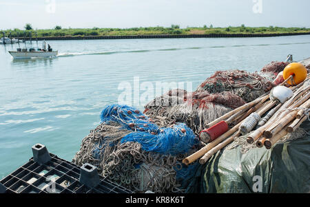 Le reti da pesca impilati in una fila sul molo Foto Stock