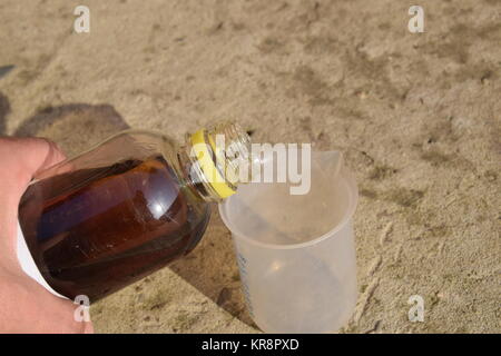 Versando il glifosato spessa soluzione in un beaker Foto Stock