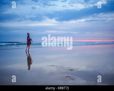Australia, Nuovo Galles del Sud, donna in piedi sulla spiaggia al tramonto Foto Stock