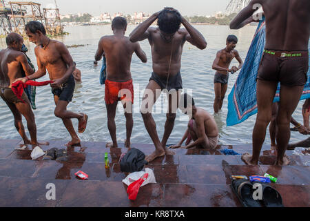 Gli uomini si bagnano al ghats accanto al Fiume Hooghly in Kolkata, India Foto Stock