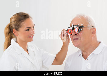 All'ottico optometrista femmina di controllo paziente la visione con telaio di prova Foto Stock