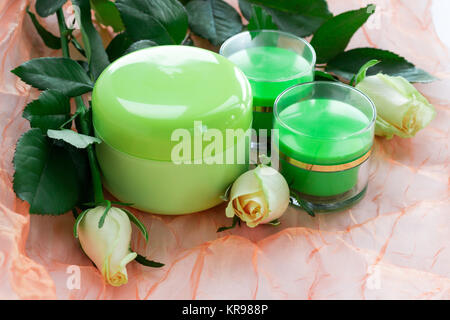 Set di tre verde flaconi cosmetici con rose bianche Foto Stock