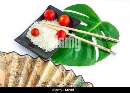 Composizione orientali di riso, pomodori, bastoncini, verde foglia, trasp Foto Stock