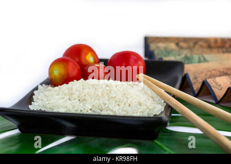 Set orientali di riso, pomodori, bastoncini, foglie verde e trasp Foto Stock