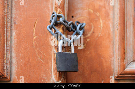 Lucchetto con catena bloccando l'ingresso di una porta di legno. Vista ravvicinata. Foto Stock
