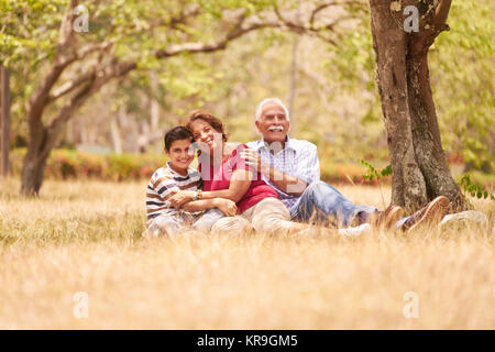 Nonni coppia Senior abbracciando giovane ragazzo sull'erba Foto Stock