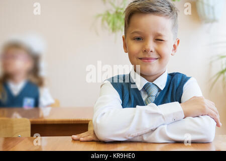 Felice schoolboy seduto alla scrivania Foto Stock