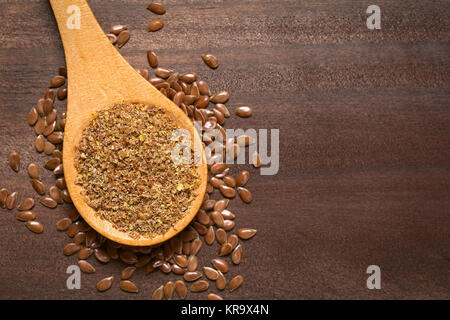 Semi di lino marroni o semi di lino e semi di lino macinati o schiacciati  in una piccola ciotola e capsule di gelatina con olio omega su sfondo  azzurro Foto stock 