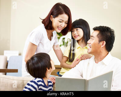 Asian genitori la madre e il padre e i due figli del figlio e figlia la lettura di un libro per raccontare una storia insieme. Foto Stock