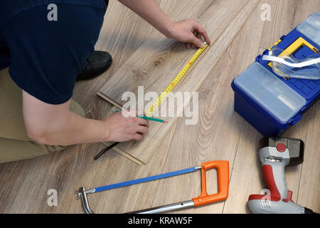 Lavoratore installazione di pavimenti in laminato. La ristrutturazione del concetto di casa. Foto Stock