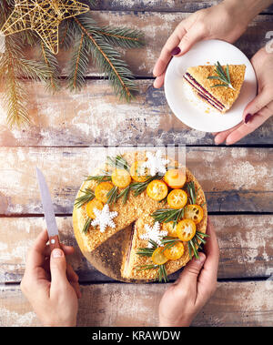 Uomo di Natale tagliati torta di miele e donna pezzo di tenuta sulla piastra a colazione. Foto Stock