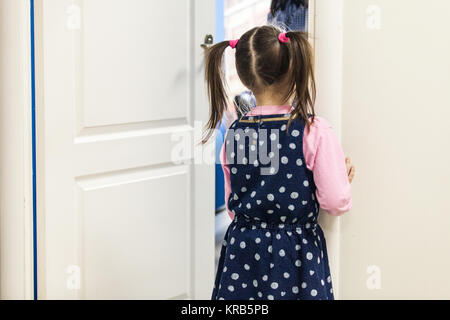 La ragazza (5-7) cercando in aula attraverso la porta vista posteriore Foto Stock