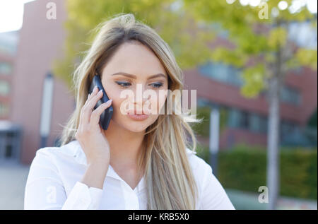 Giovani caucasici donna bionda chiamando al quartiere finanziario all'aperto Foto Stock