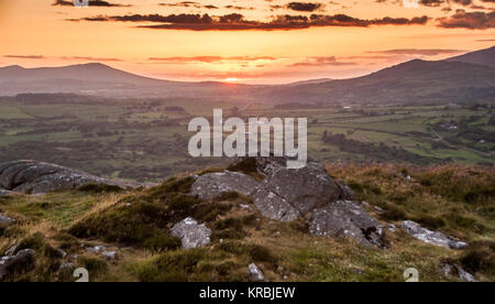 Il tramonto proietta un cielo rosso oltre le montagne o Bwlch Mawr sul Lleyn Peninsula in Galles del Nord, visto dal Moel-y-Gest nel Parco Nazionale di Snowdonia. Foto Stock