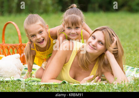 La madre e le sue due figlie si trovano su ogni altra sull'erba verde Foto Stock